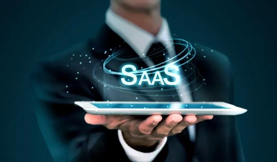 Person in a suit holding a tablet with a glowing SaaS hologram above it