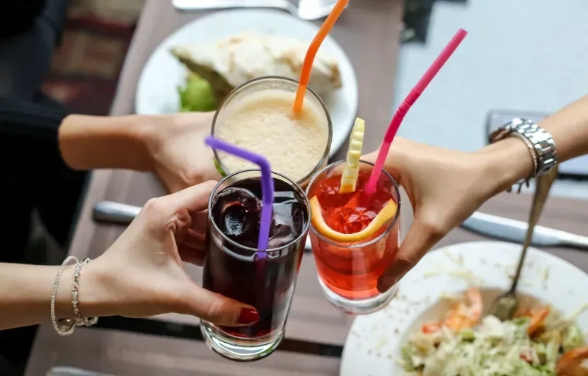 Three people clinking drinks together over a restaurant table