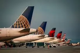 United, Delta and American Airlines jets parked in a row at an airport gate